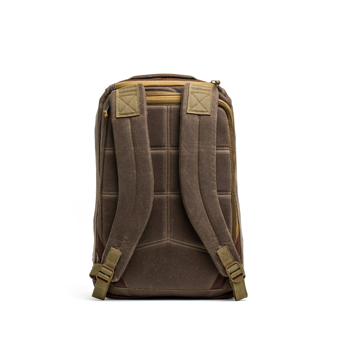 The GORUCK GR1 USA - Heritage rucksack in brown waxed canvas features padded shoulder straps and a top handle, displayed from the back on a white background.