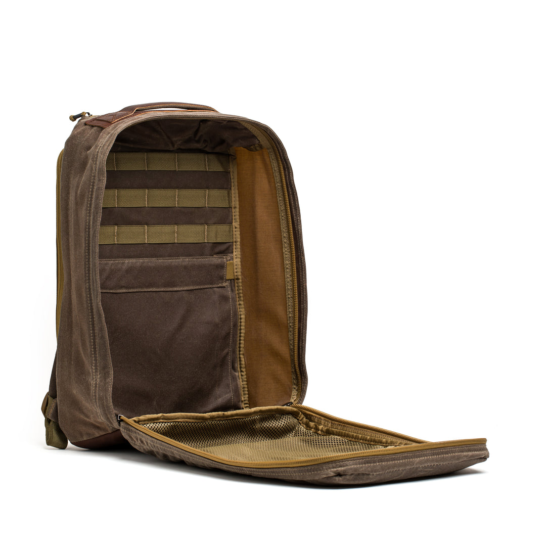 The GORUCK GR1 USA - Heritage backpack in brown stands upright with its main compartment open, showcasing interior pockets and a mesh organizer.