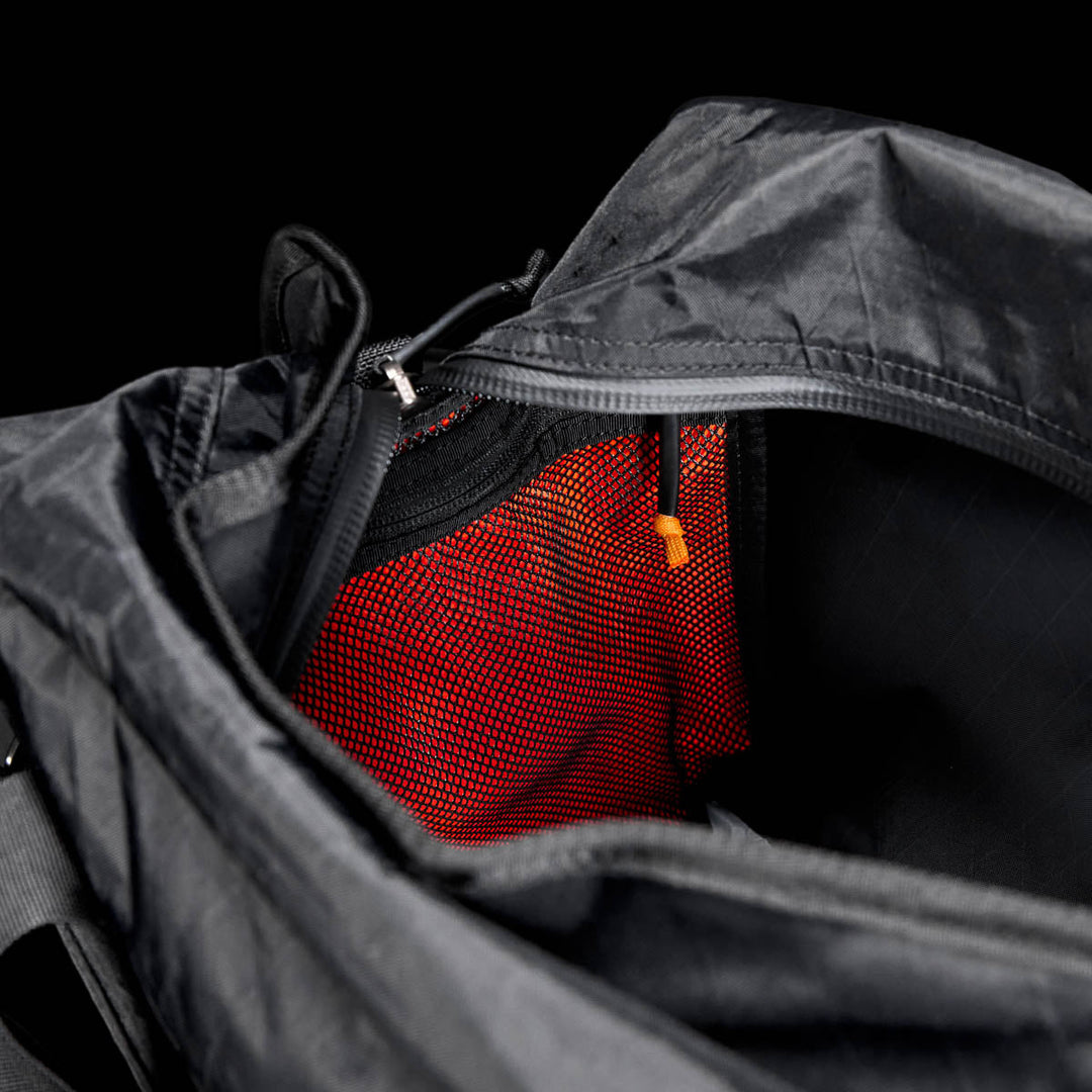 Open Kit Bag - X-PAC, featuring a visible red mesh pocket and an orange zipper pull, shown on a black background.