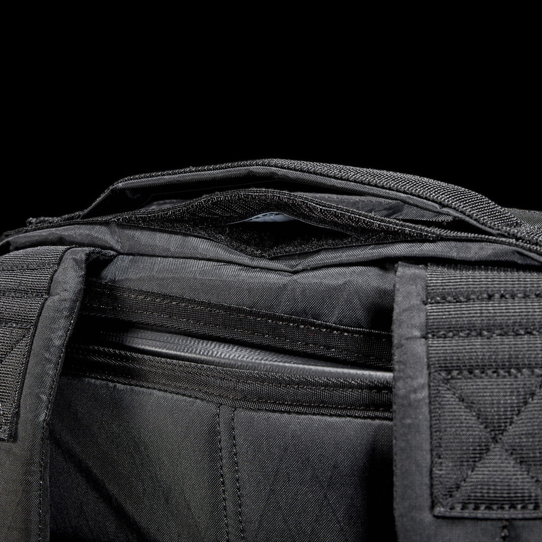 Close-up of the GR0 - X-PAC by GORUCK, showing its zippered compartment and handles made from lightweight X-PAC material, set against a black background.