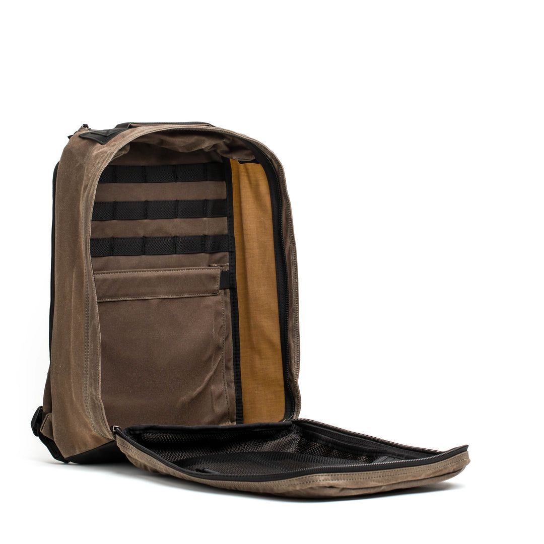 The GR1 USA - Heritage by GORUCK is an open tan backpack with multiple compartments, crafted from durable waxed canvas, shown against a white background.