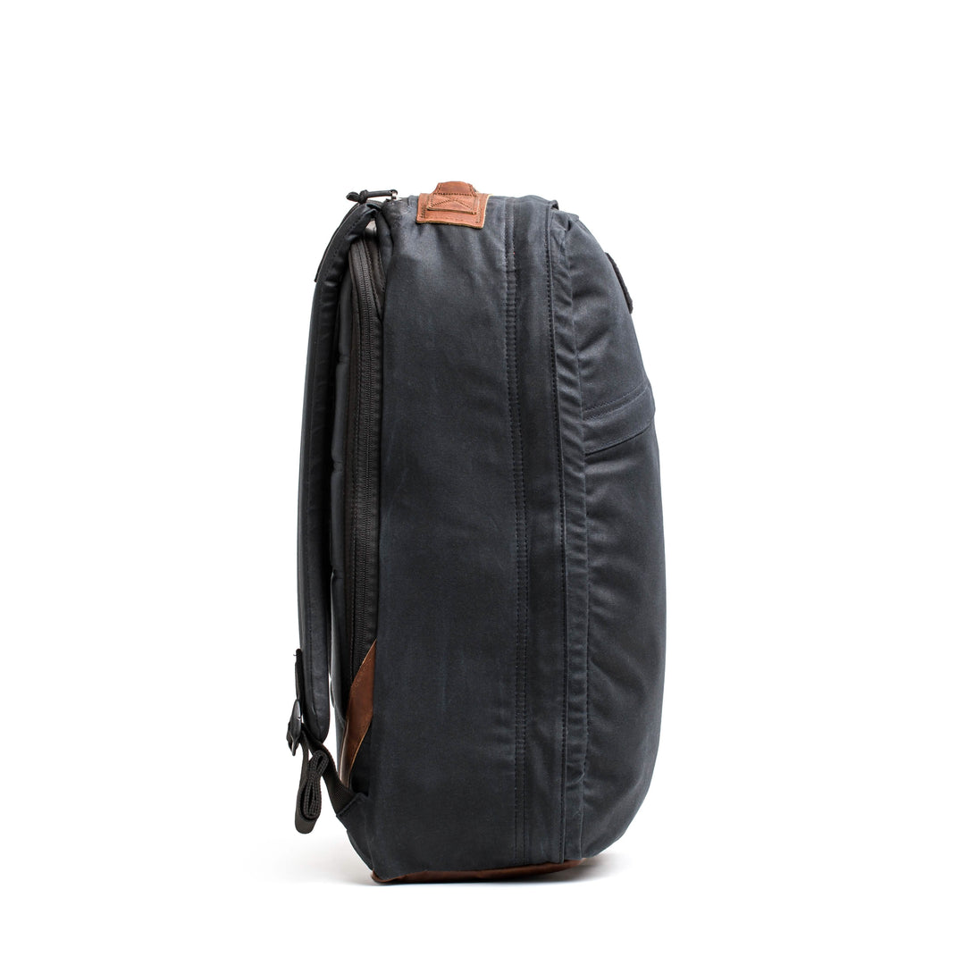 A side view of the GR1 USA - Heritage by GORUCK features a gray rucksack with brown accents, adjustable straps, and crafted from waxed duck canvas, all set against a white background.