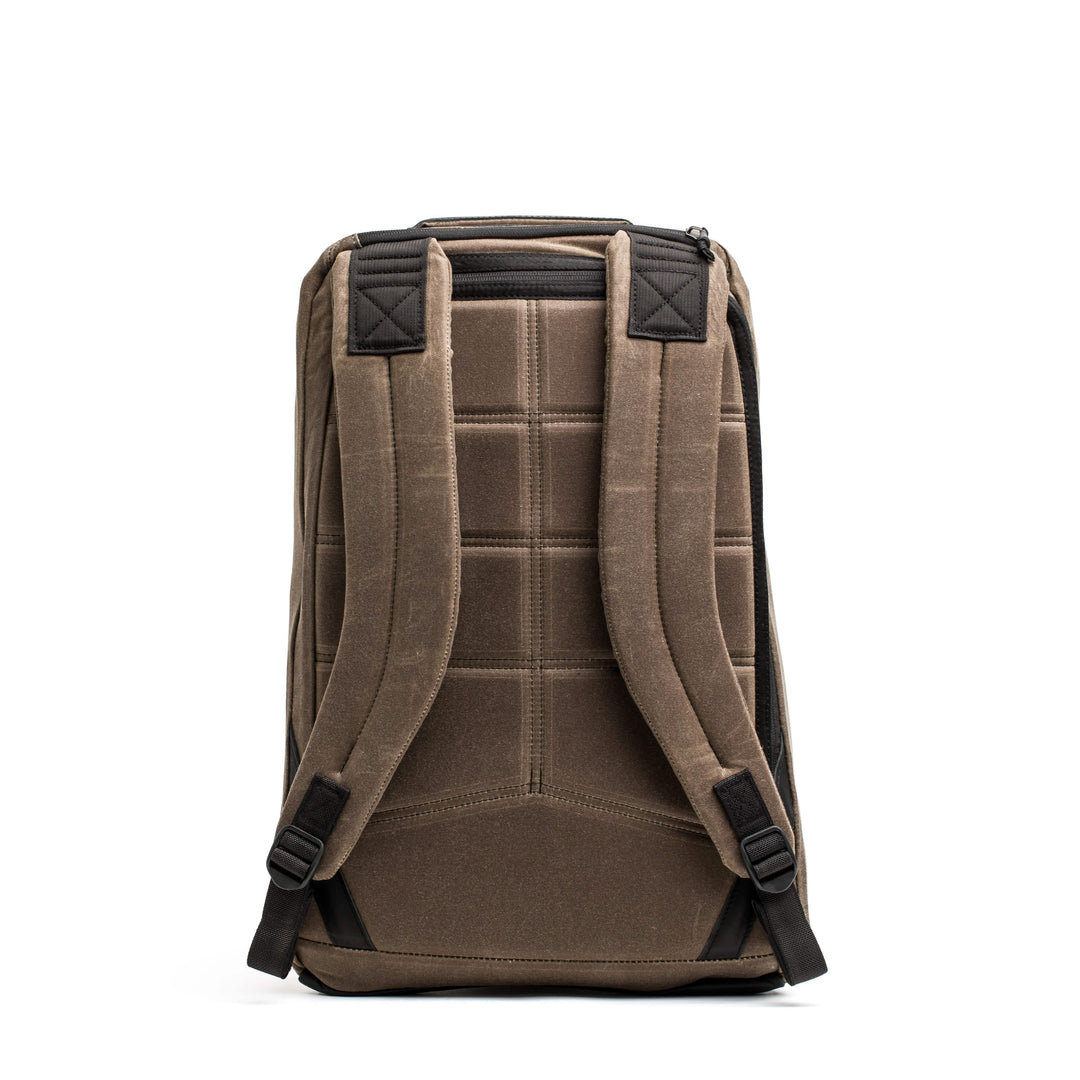 Seen from the back, the GORUCK GR1 USA - Heritage is a brown rectangular backpack crafted from waxed duck canvas, featuring padded shoulder straps and a zippered top.