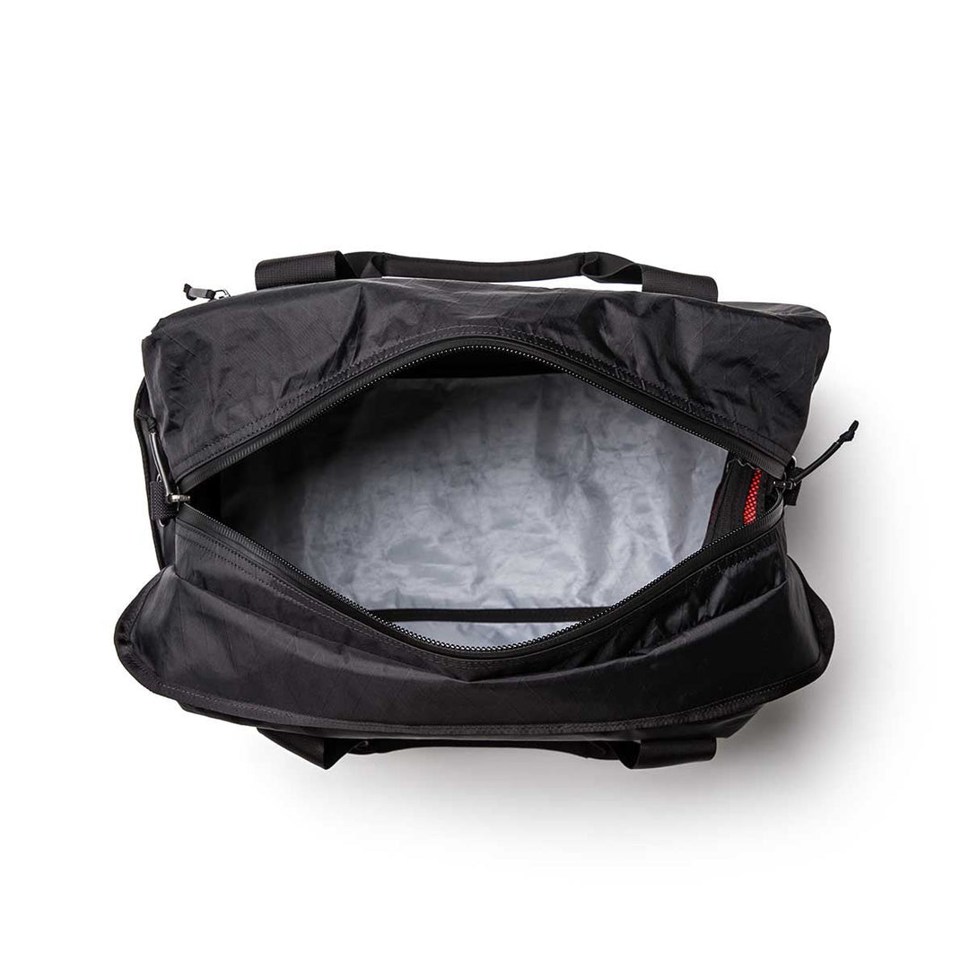Top view of the Kit Bag - X-PAC, inspired by the aviator kit bag and made with durable X-PAC VX21 material, displaying its empty gray interior and visible zipper.