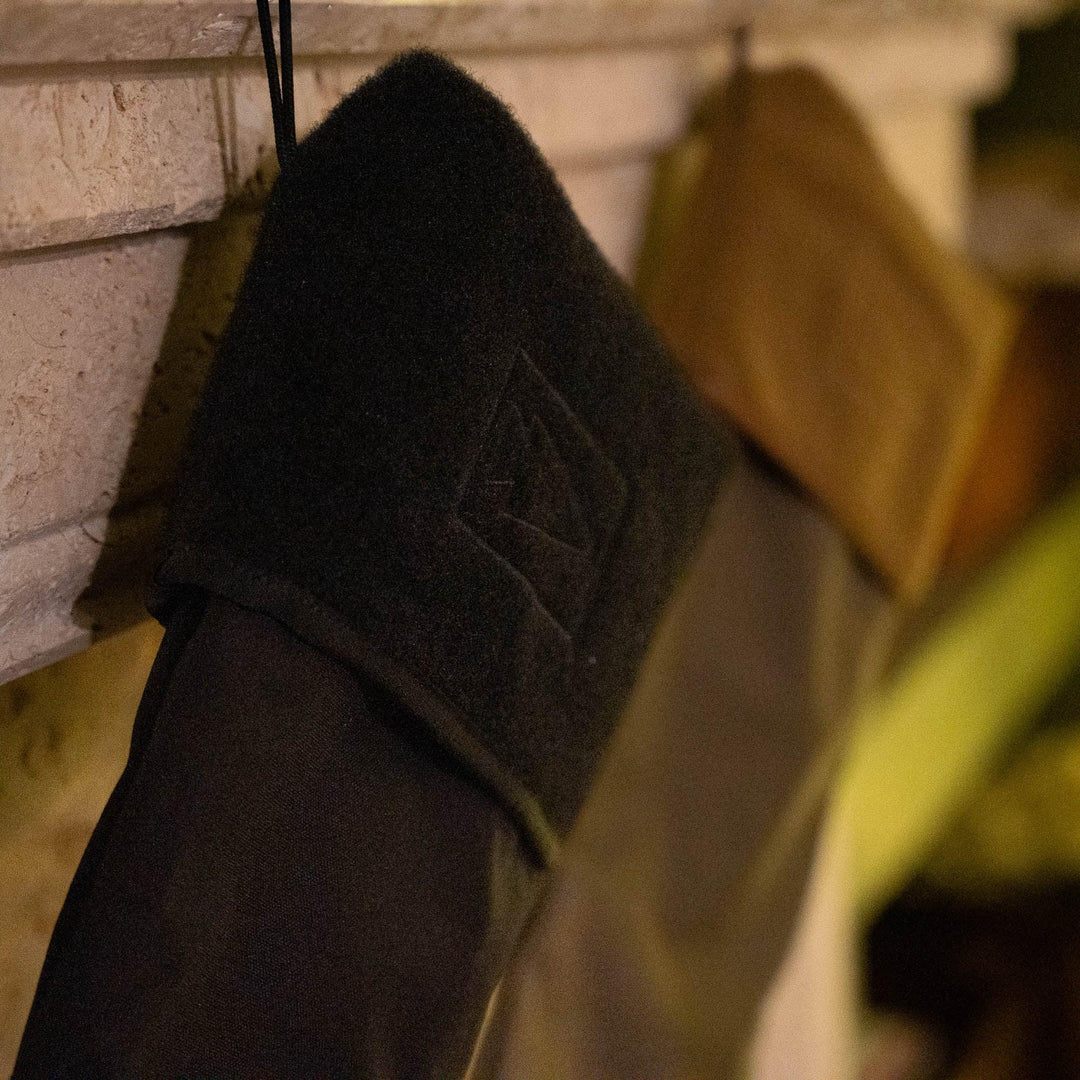 GORUCK black tactical stocking with Velcro patch hanging on a stone mantel