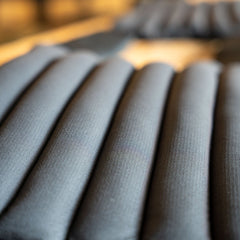 Close-up view of several black cylindrical cushions, resembling the padding in the Achilles | Men's Weighted Vest, arranged in parallel rows.
