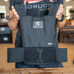 Person holding a black Achilles | Men's Weighted Vest featuring thick straps and a Velcro waistband, designed for safe and effective premium training.