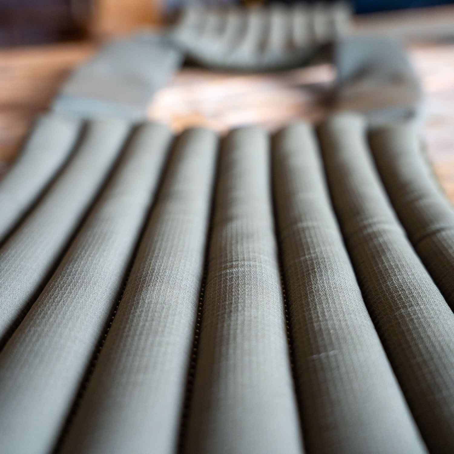 Close-up of an olive green inflatable sleeping pad with horizontal air chambers, ideal for relaxing after an intense workout wearing your Achilles | Men's Weighted Vest.
