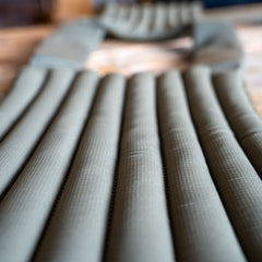Close-up of an olive green inflatable sleeping pad with horizontal air chambers, ideal for relaxing after an intense workout wearing your Achilles | Men's Weighted Vest.