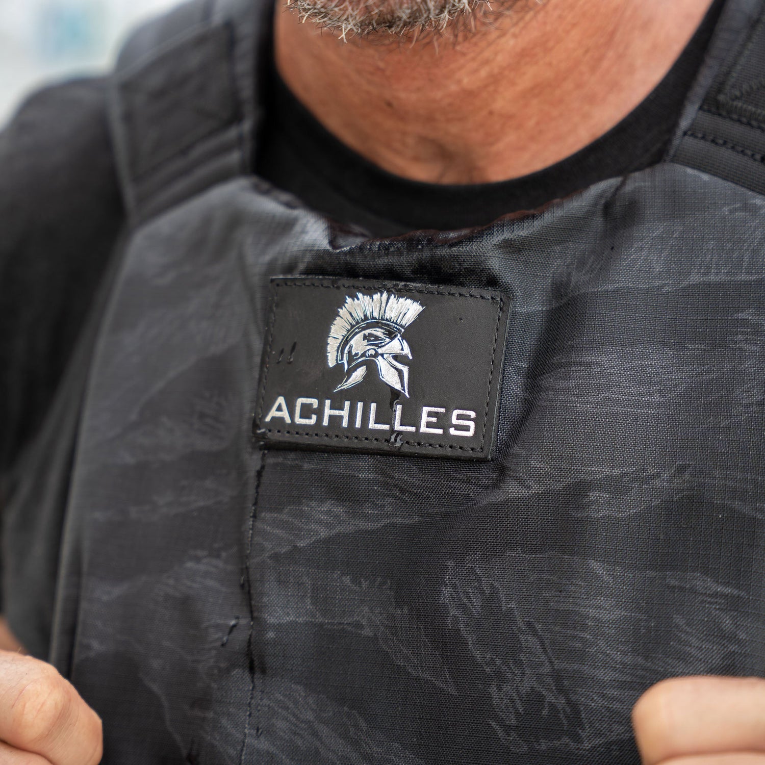 Close-up of a person wearing the Achilles | Men's Weighted Vest, featuring a Spartan helmet logo patch.