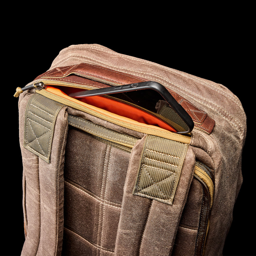 A tablet partially tucked into the top pocket of the GORUCK GR1 USA - Heritage backpack is set against a black background.