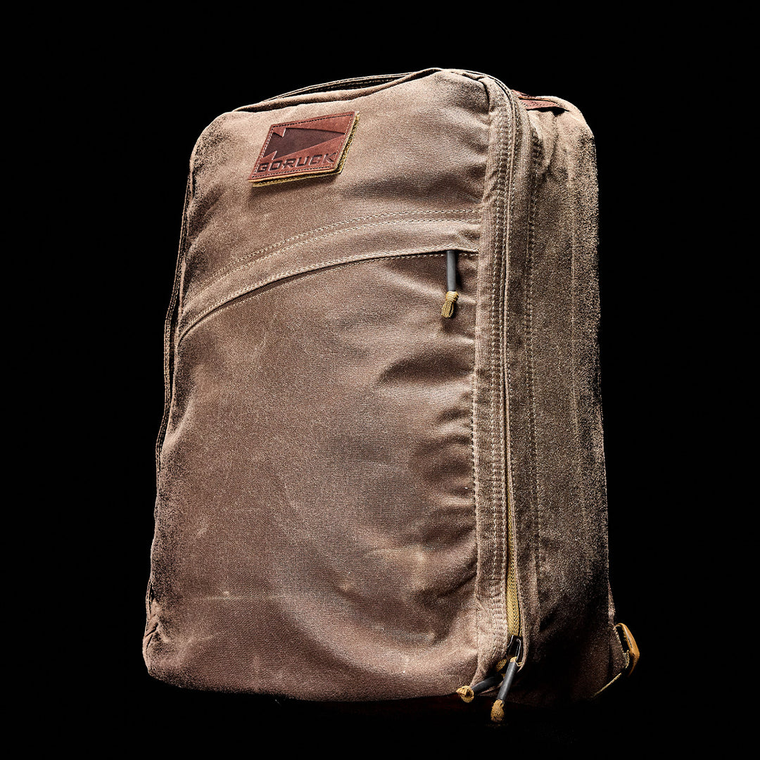 The GORUCK GR1 USA - Heritage backpack in brown stands upright against a black background, its heritage design catching the eye.