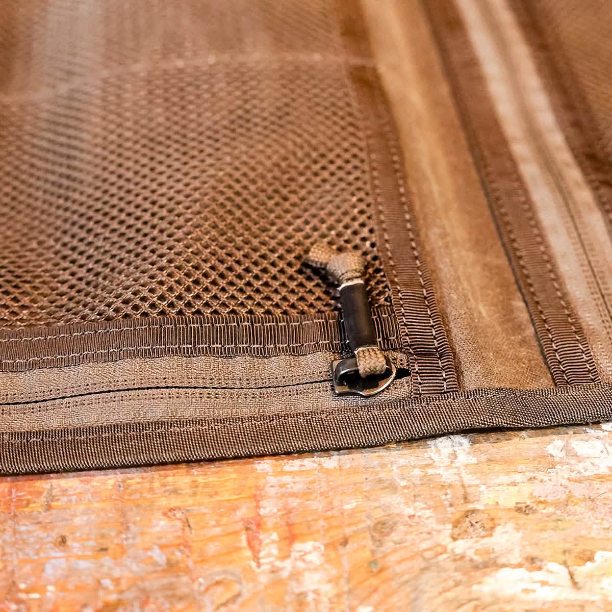 Close-up of the GORUCK Wire Dopp - Waxed Canvas pouch on a wooden surface, ideal for EDC organization and keeping your travel essentials neatly stored.