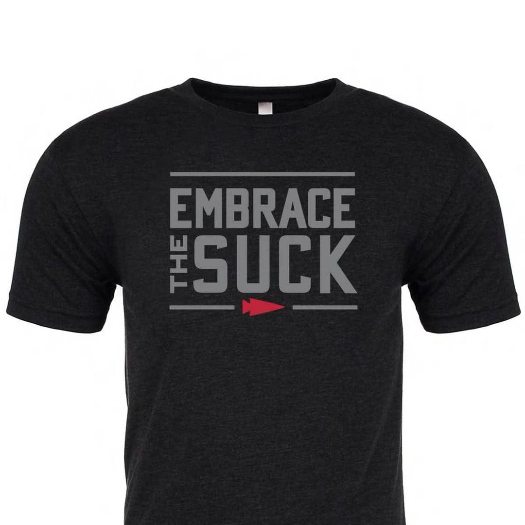 The Embrace the Suck Tee - Tri-Blend by vendor-unknown is a black shirt with "EMBRACE THE SUCK" in bold gray letters and a small red arrow underneath, featuring the official USMC motto.