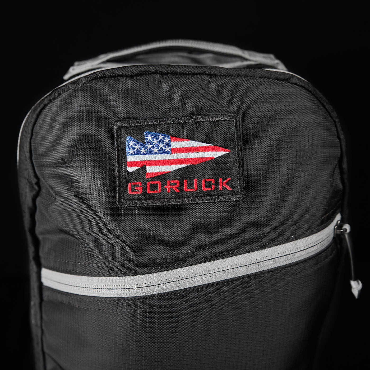 Black backpack with a patch showing a U.S. flag arrow and the word 