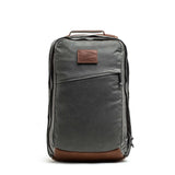 The GORUCK GR2 - Heritage Waxed Canvas backpack features gray waxed canvas, brown Red Wing leather accents, a front zipper pocket, and a convenient top handle—an upright, stylish ruck perfect for travel.