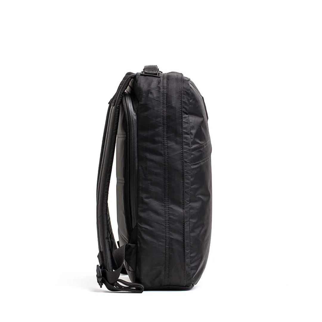 Side view of the black GORUCK GR0 - X-PAC backpack standing upright against a white background, highlighting its lightweight and waterproof X-PAC material.