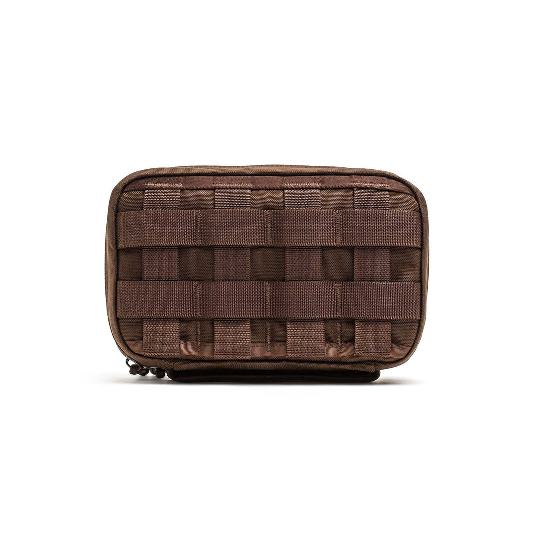 The GR1 Field Pocket is a small brown tactical pouch with front webbing, ideal for organizing electronics or attaching to gear and bags.