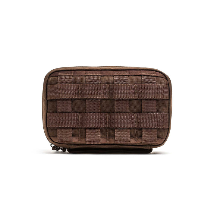 The GR1 Field Pocket is a small brown tactical pouch with front webbing, ideal for organizing electronics or attaching to gear and bags.