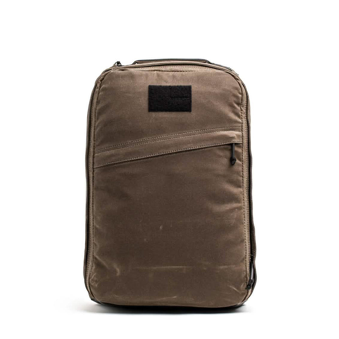 The GORUCK GR1 USA - Heritage is a retro canvas rucksack in rich brown featuring a front zipper pocket and black patch on top, set against a crisp white background.