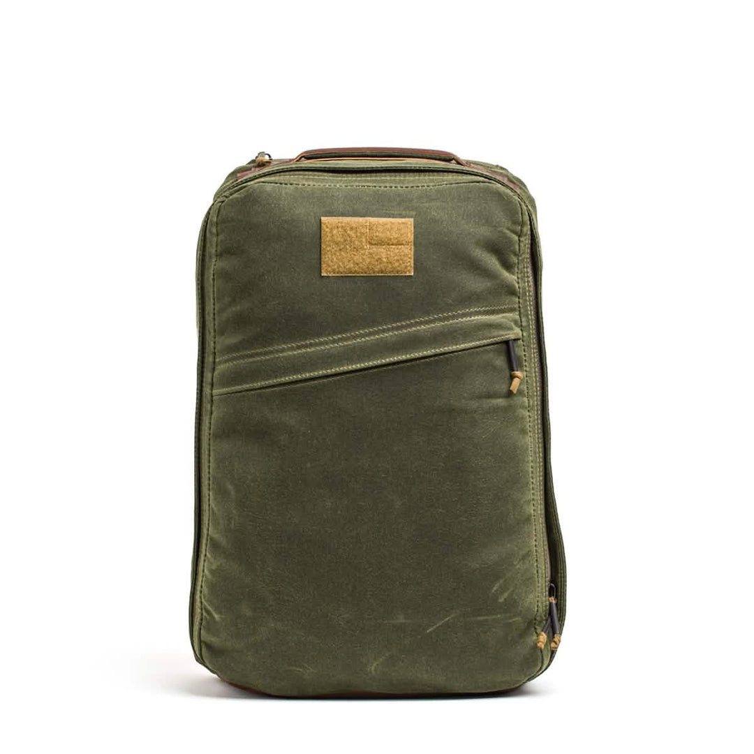 The GR1 USA - Heritage by GORUCK is a stylish and durable waxed canvas rucksack featuring a front zipper pocket and a tan patch on top.