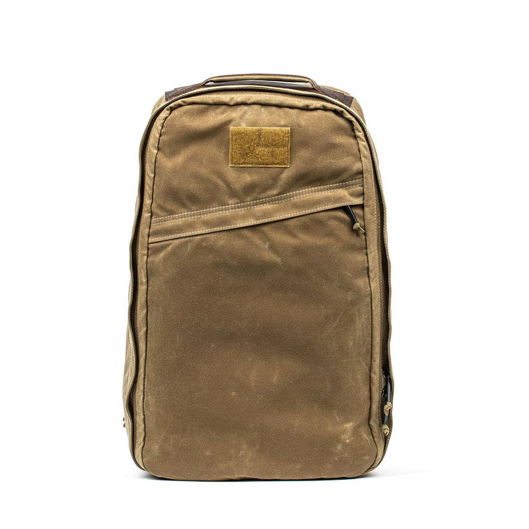 The GR1 USA - Heritage rucksack by GORUCK in rich brown, with a front pocket and top handle, stands upright against a pristine white background.