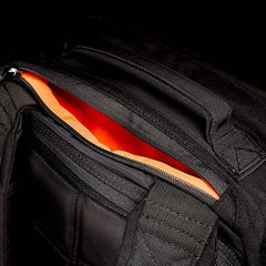 The GORUCK GR1 USA rucksack, in sleek black and made from durable CORDURA, has an open zipper that reveals a vibrant orange interior.