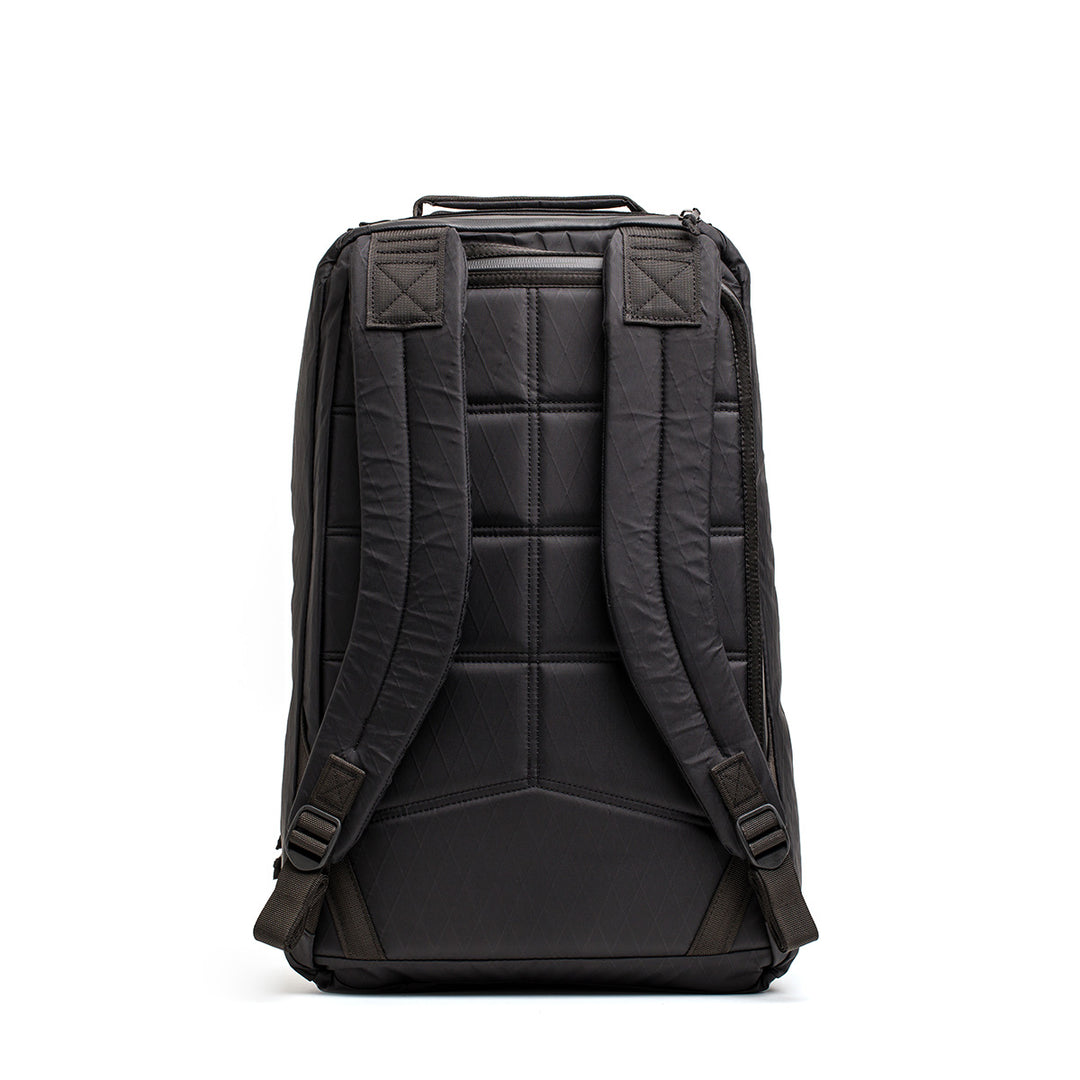 The GORUCK GR1 USA - X-PAC is a black backpack with padded straps, geometric stitching, and AquaGuard zippers for water resistance, shown from the back on a white background.