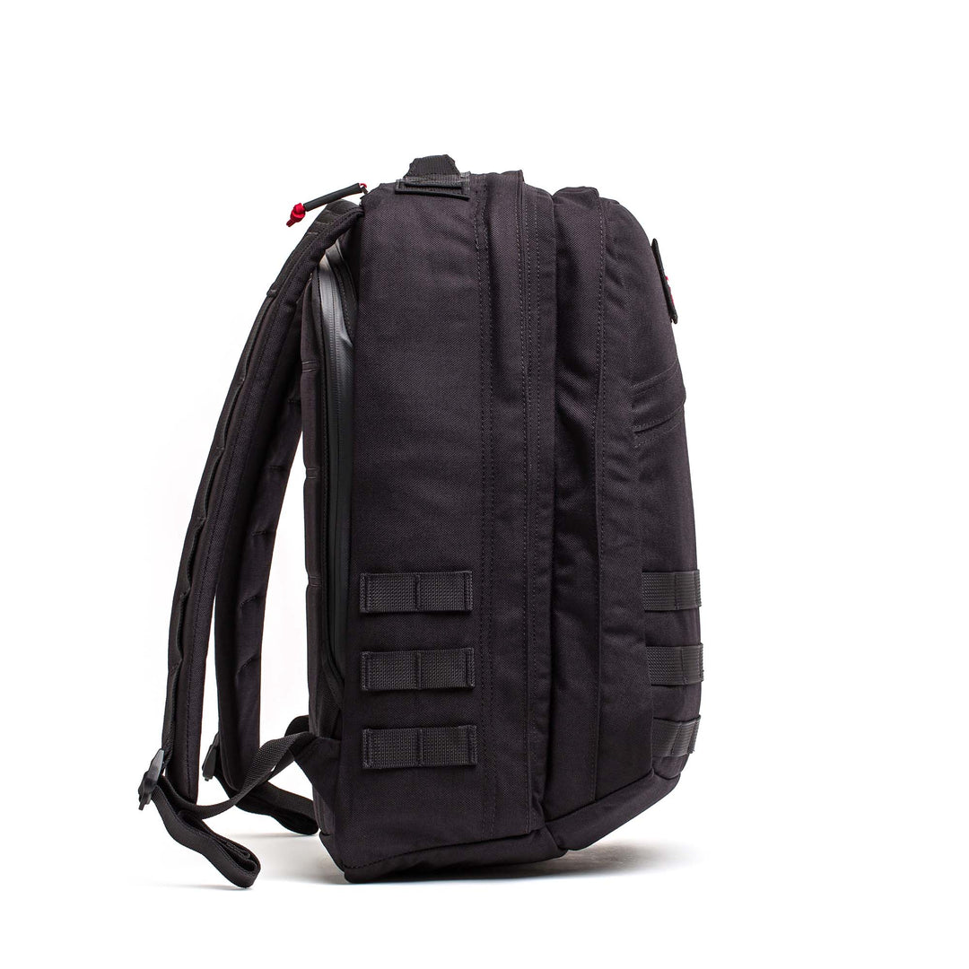 The GORUCK GR2 backpack, shown upright from the side in black, features multiple compartments and straps, making it an ideal carry-on travel bag.