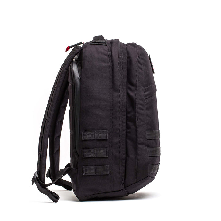 The GORUCK GR2 backpack, shown upright from the side in black, features multiple compartments and straps, making it an ideal carry-on travel bag.