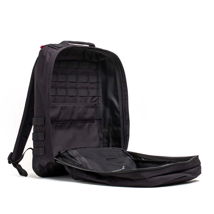 A black GORUCK GR2 rucksack is shown open, revealing its roomy interior and multiple compartments—ideal for use as a carry-on travel bag.
