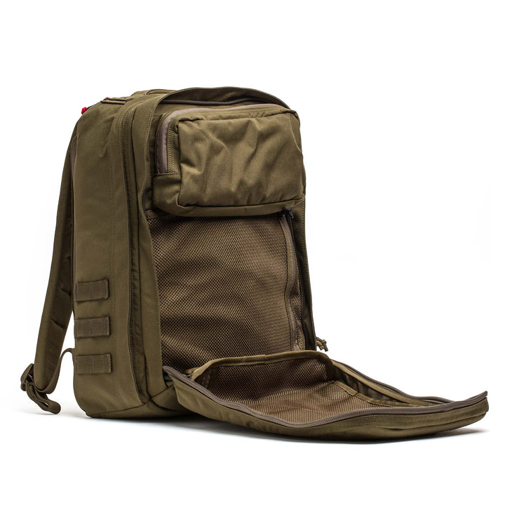 The GORUCK GR2, a brown travel backpack, is shown with its main compartment open, revealing inner mesh pockets.