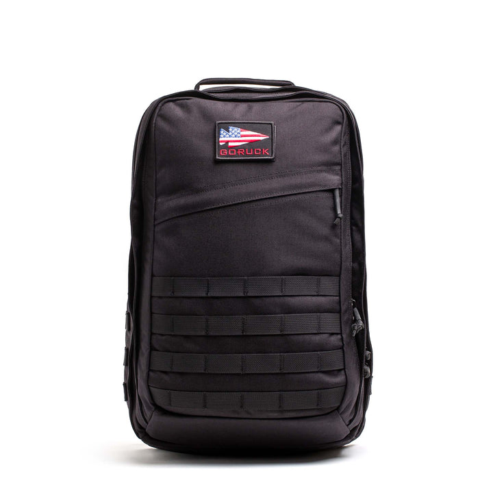 The GORUCK GR2 is a black backpack featuring a rectangular front pocket, lower front MOLLE webbing, and an American flag patch—engineered with Special Forces quality for dependable travel and ruck adventures.