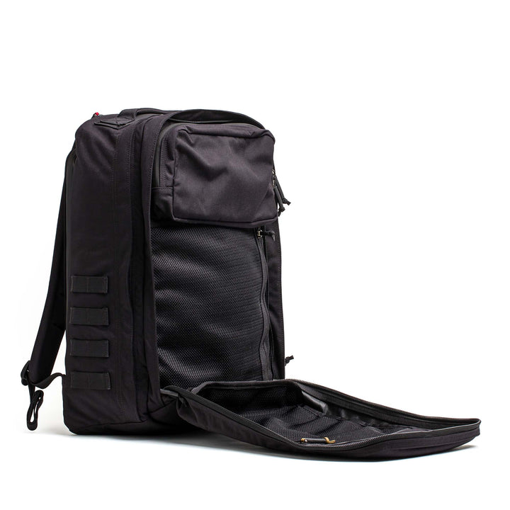 The GORUCK GR2 black carry-on backpack stands upright with its front compartment unzipped, showing inner pockets—designed for efficient organization inspired by Special Forces backpack features.