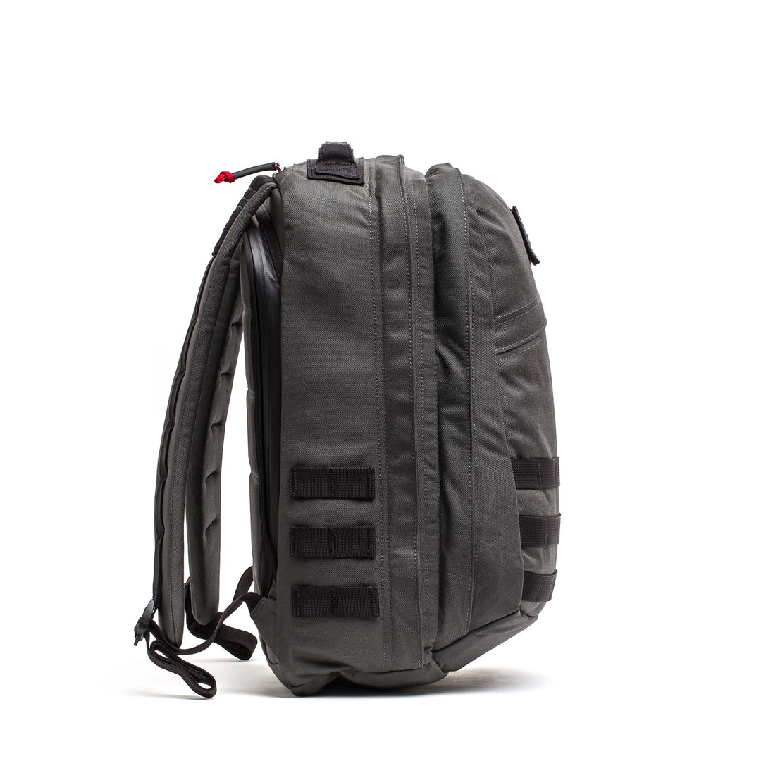 Side view of the GORUCK GR2 gray travel backpack with padded straps and multiple webbing loops, highlighting Special Forces-grade durability against a white background.
