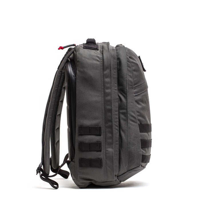 Side view of the GORUCK GR2 gray travel backpack with padded straps and multiple webbing loops, highlighting Special Forces-grade durability against a white background.