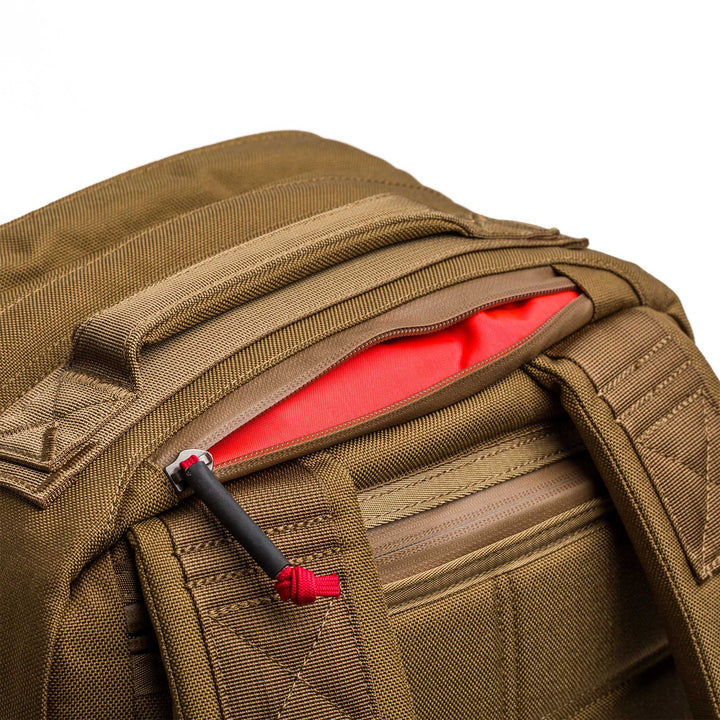Close-up of the GORUCK GR2 backpack, featuring a partially open zipper that reveals its bright orange interior lining.