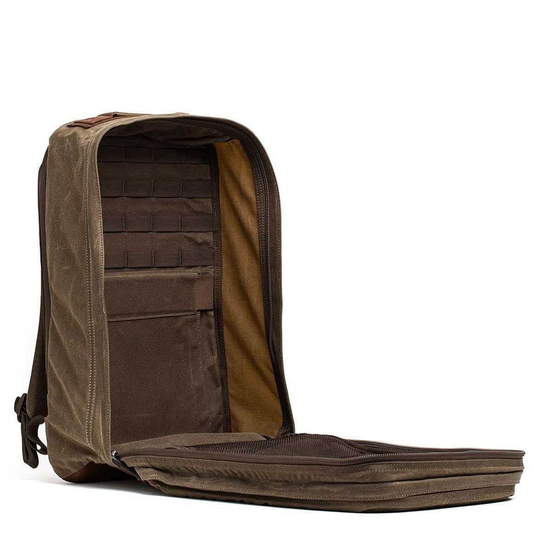 The GORUCK GR2 - Heritage Waxed Canvas is a brown backpack with a fully opening main compartment, revealing interior pockets, storage slots, and a bombproof laptop compartment for secure organization.