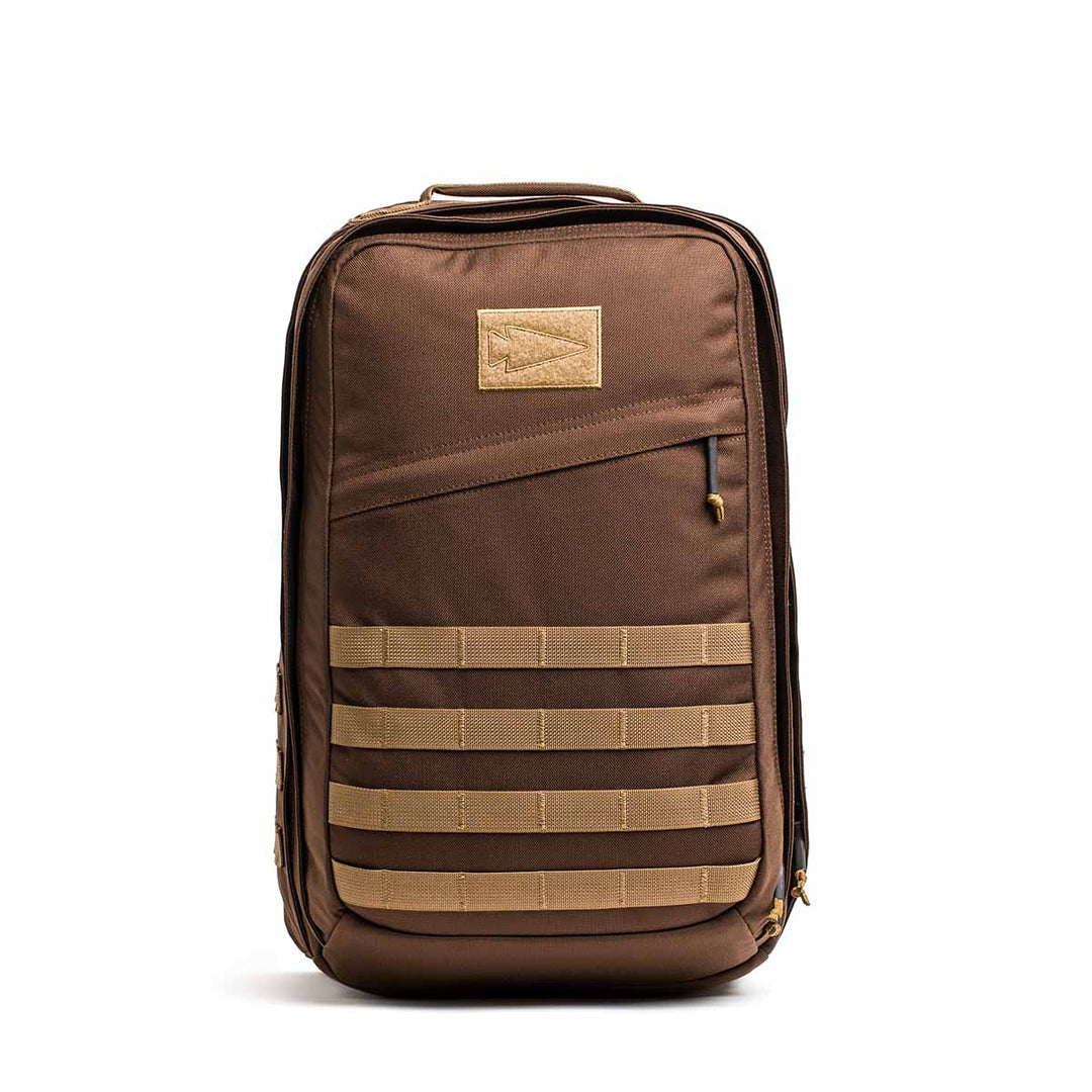 The GORUCK GR2 is a brown tactical backpack with tan accents, front zipper pocket, and horizontal webbing straps—ruggedly designed after Special Forces packs and ideal as a carry-on travel bag.