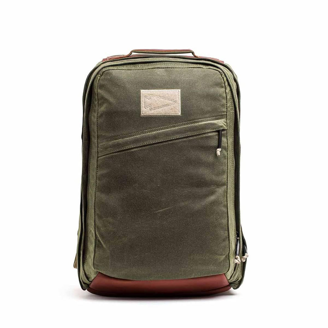 The GORUCK GR2 - Heritage Waxed Canvas backpack features olive green waxed canvas, brown Red Wing Leather accents, a front zipper pocket, and a top rectangular patch—ideal for stylish travel.