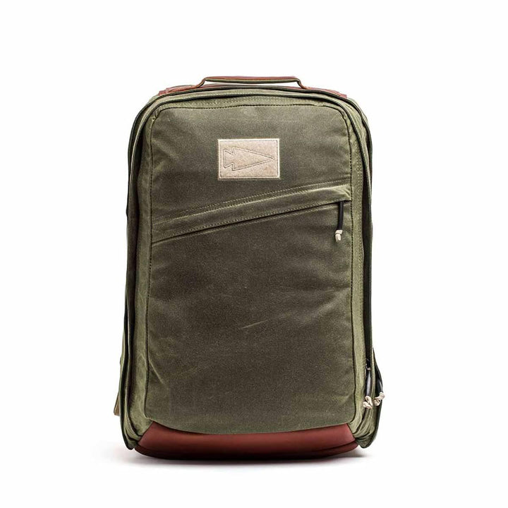 The GORUCK GR2 - Heritage Waxed Canvas backpack features olive green waxed canvas, brown Red Wing Leather accents, a front zipper pocket, and a top rectangular patch—ideal for stylish travel.