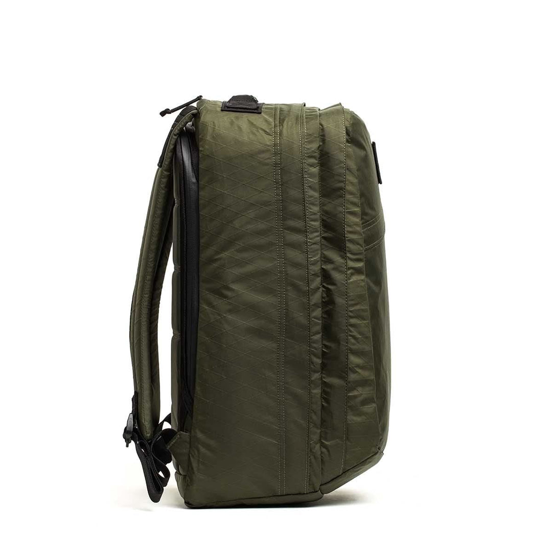 Side view of the green GORUCK GR2 X-PAC backpack with black zippers and adjustable straps, standing upright—ideal for anyone seeking a durable, waterproof pack.