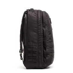 The GR2 - Cordura backpack stands upright, side view, featuring multiple webbing straps and zippers—designed for rugged durability and perfect as a carry-on travel bag.