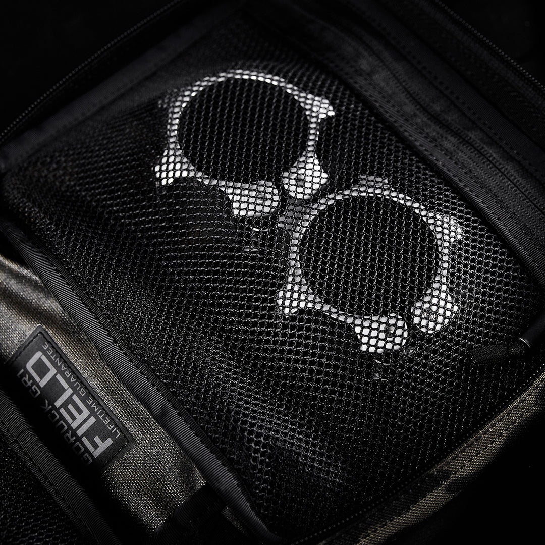 Two metallic handcuffs stored in a zippered mesh pocket inside the GORUCK GR2 Field Pocket, crafted from rugged 1000D Cordura.