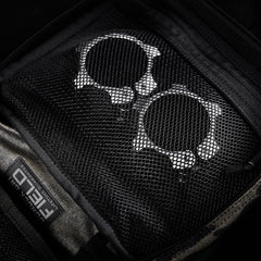 Two metallic handcuffs stored in a zippered mesh pocket inside the GORUCK GR2 Field Pocket, crafted from rugged 1000D Cordura.