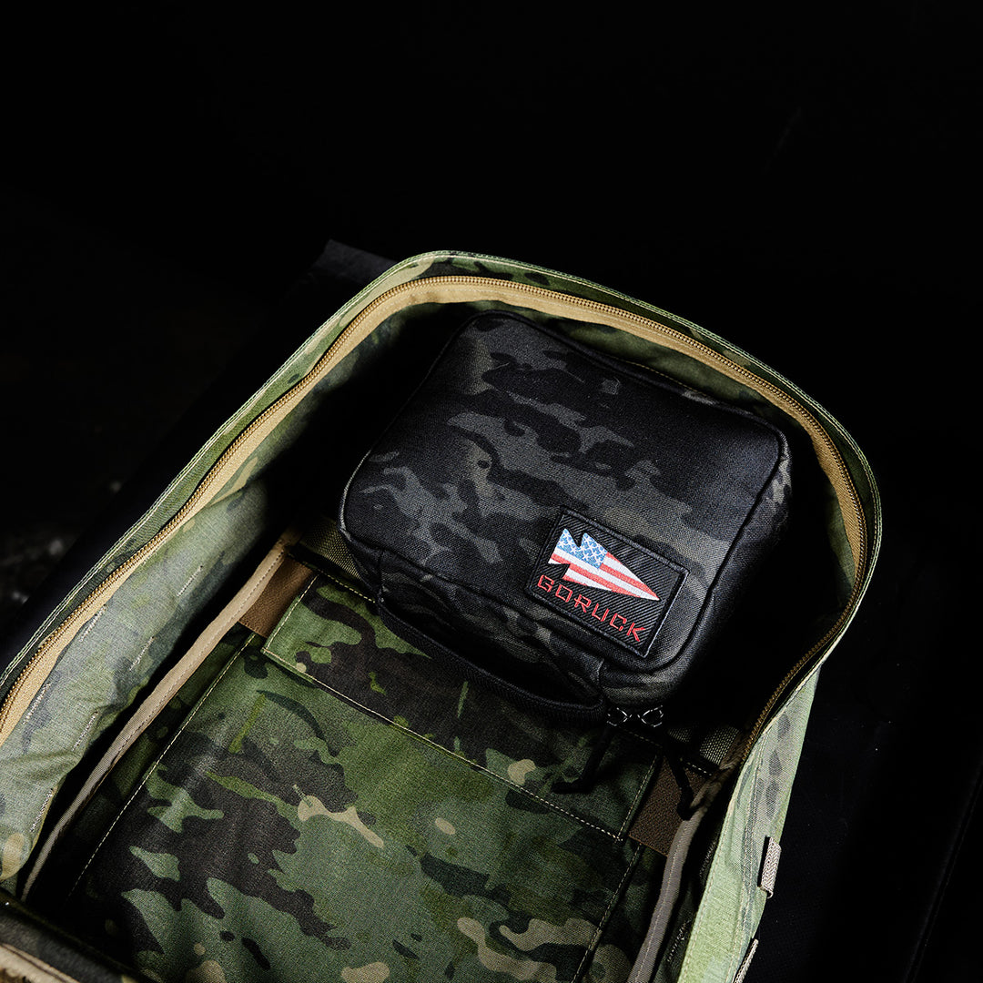Open your GR2 Field Pocket by GORUCK to reveal its camo interior, MOLLE webbing, and a black Cordura pouch inside with an American flag and "GORUCK" patch.