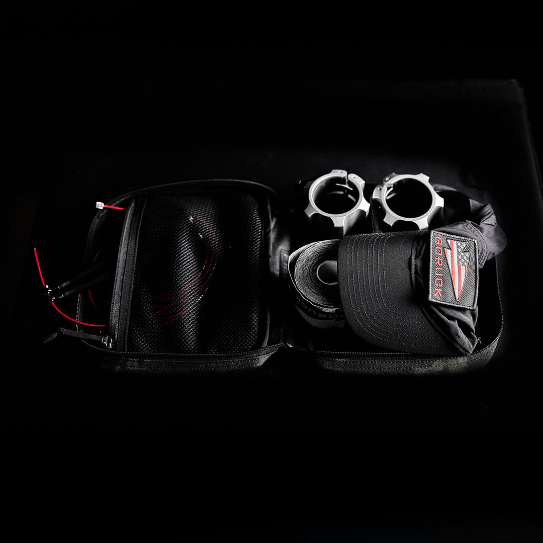 Open black GORUCK GR2 Field Pocket with a hat, two metal objects, red cable, and various gear inside; features an electronics organizer and MOLLE webbing accents against a black background.