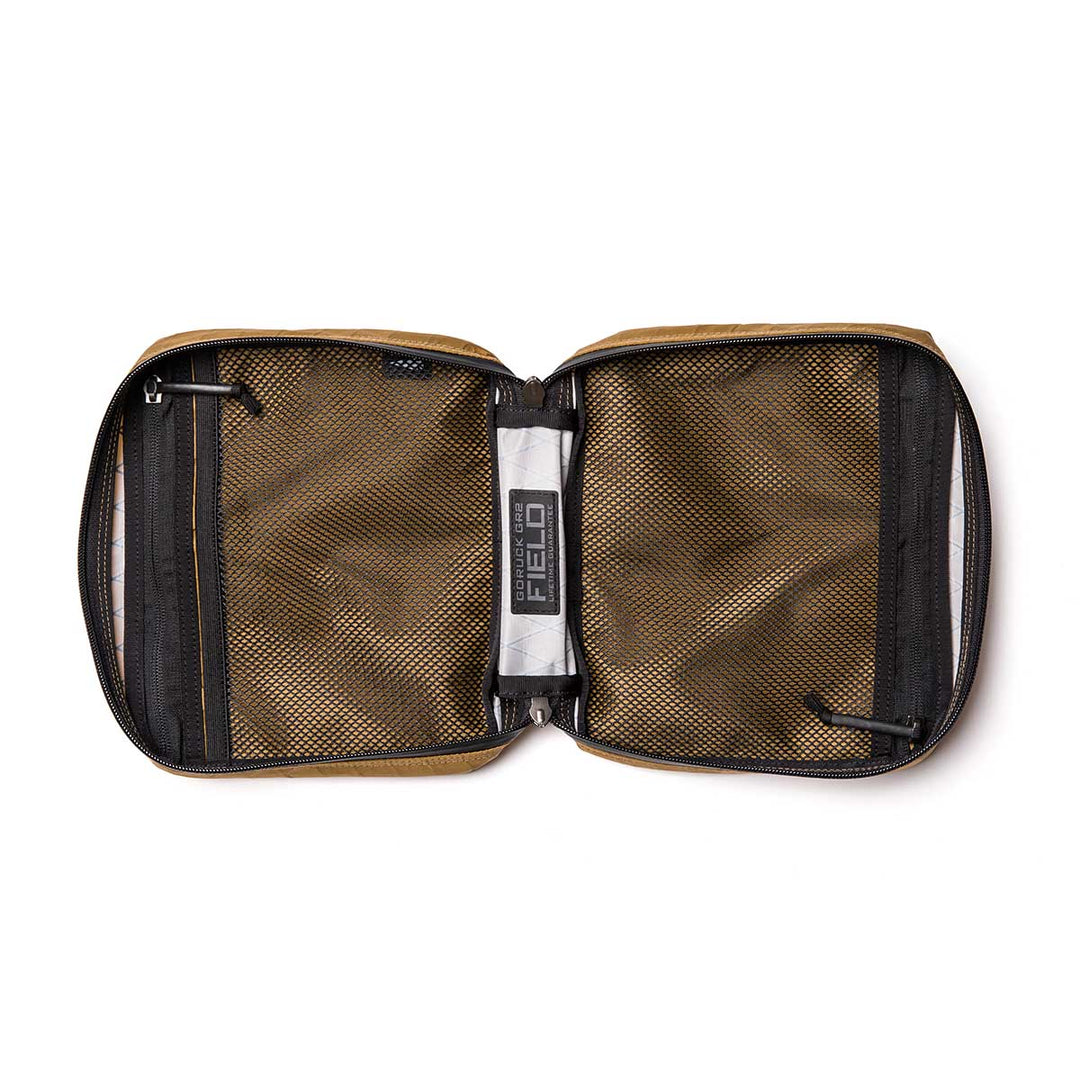 The GORUCK GR2 Field Pocket - X-PAC is an open brown zippered pouch with mesh pockets, made from waterproof fabric, featuring an interior label that reads "FIELD".