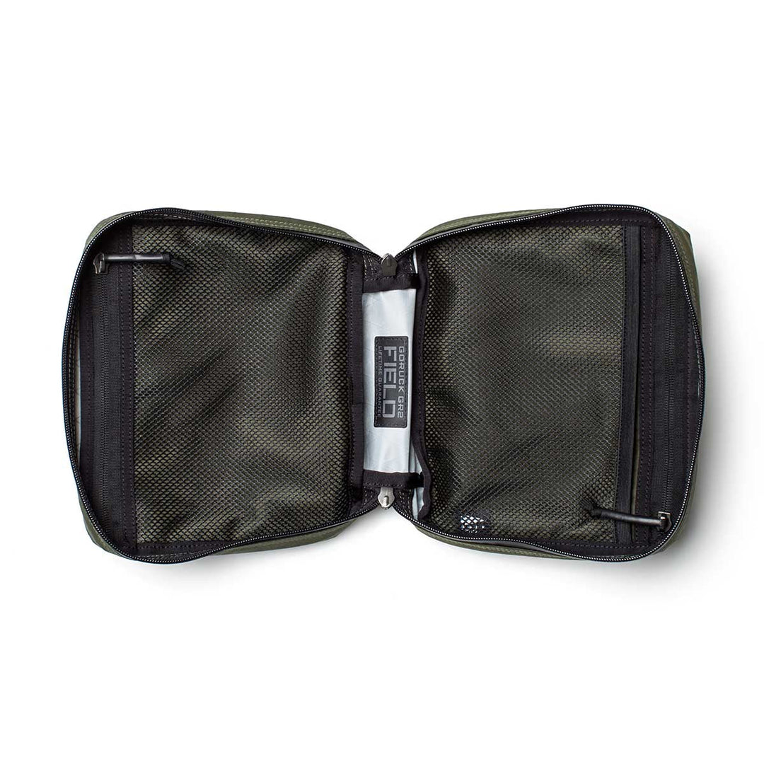 The GORUCK GR2 Field Pocket - X-PAC is a green waterproof pouch with mesh zippered pockets, ideal for organizing electronics; features a "FIELD" label at the center.