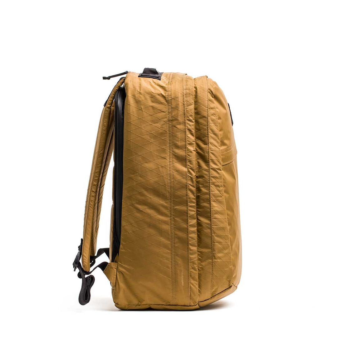 The GORUCK GR2 X-PAC backpack in mustard yellow stands upright, displaying its waterproof X-PAC material, side profile, and padded shoulder straps—built for any adventure.